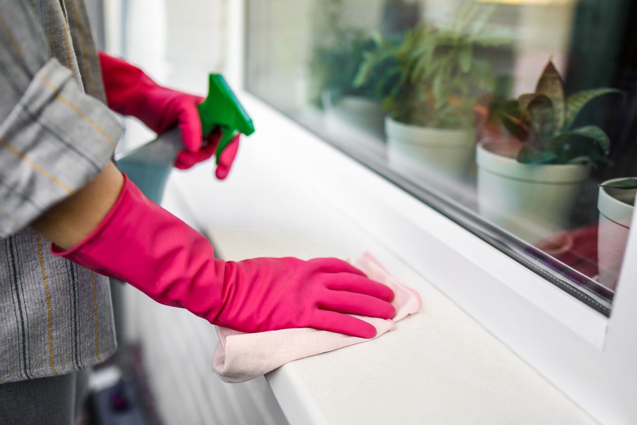 services-04 Close-up of hands in pink gloves using spray bottle and cloth indoors.
